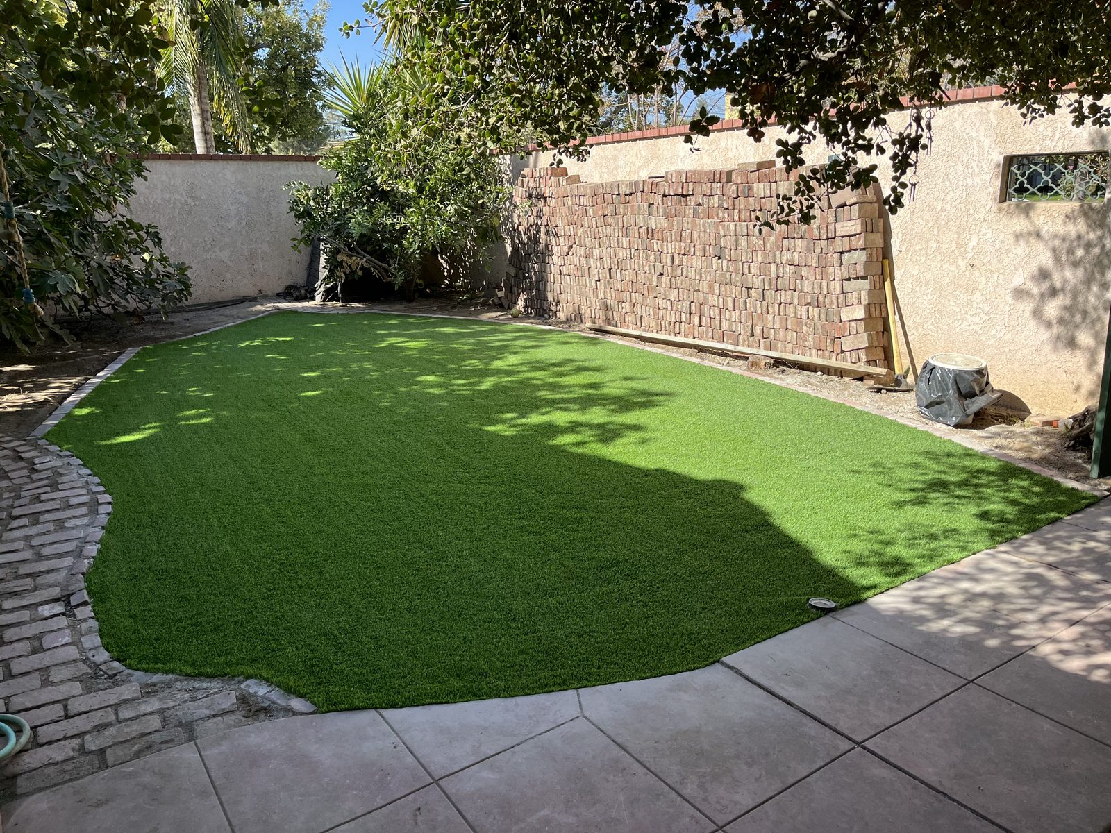 Backyard artificial turf bordered by paver patio