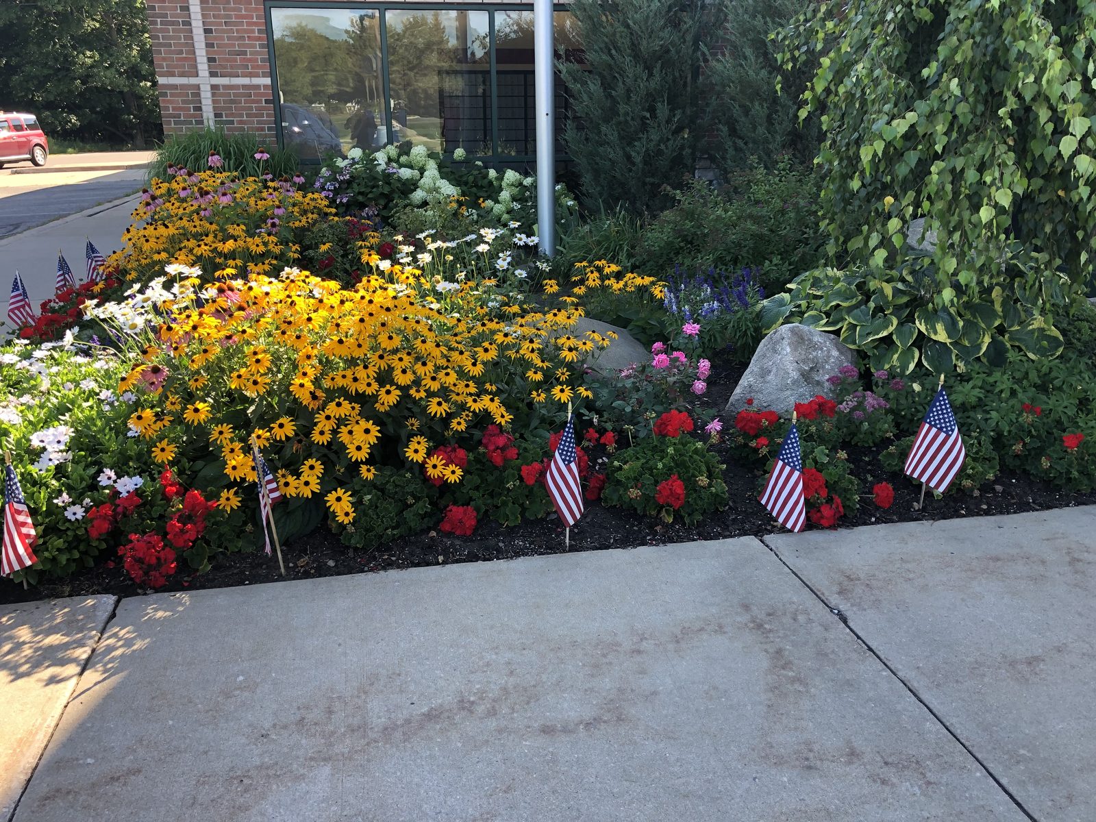 Flower beds in full bloom along a concrete walkway
