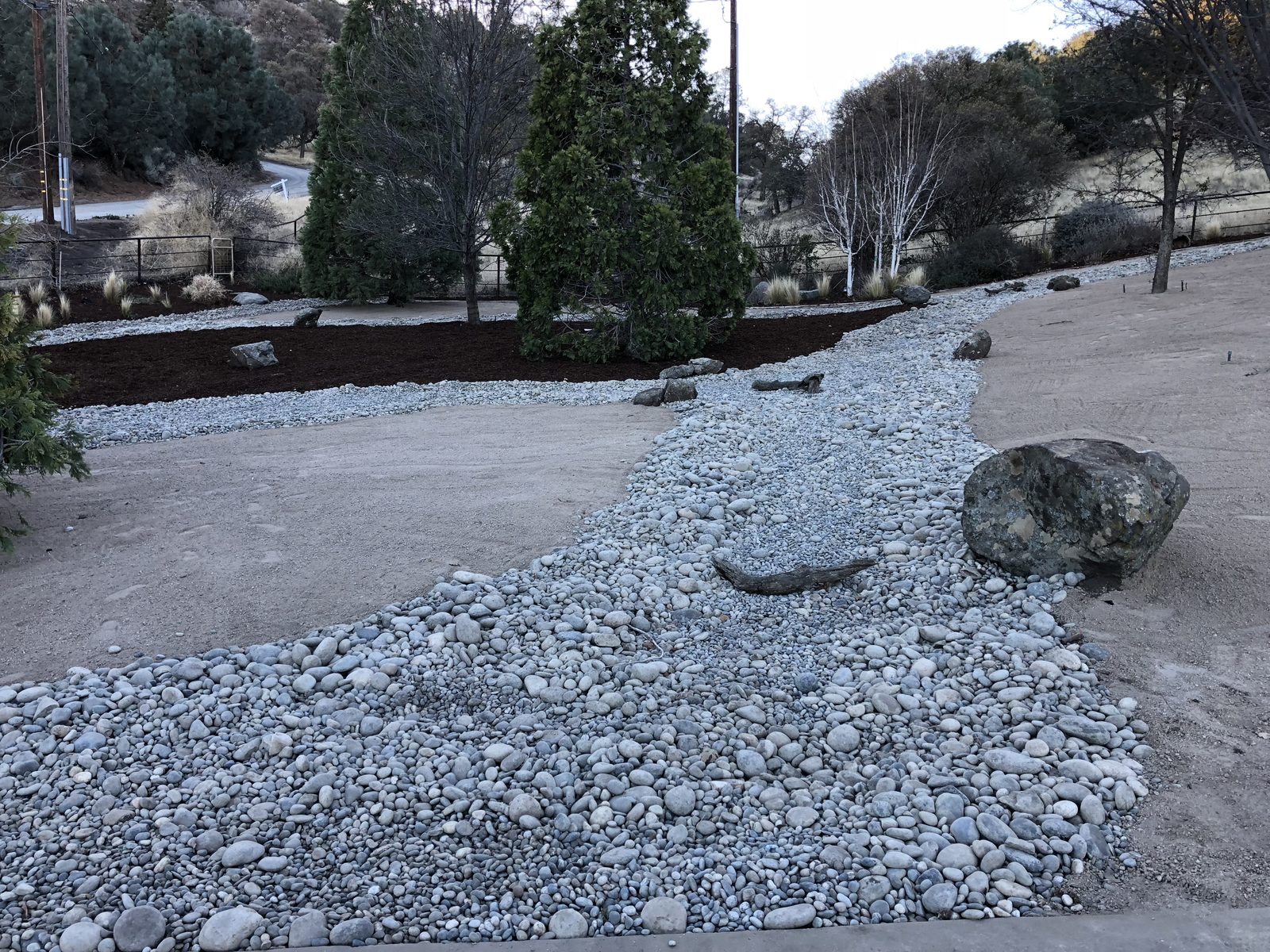 River rock dry creek with boulders and native trees